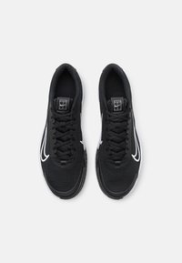 Zapatillas deportivas negras con una parte superior texturizada, acentos en blanco en el swoosh, cordones redondos y una suela acolchada para mayor soporte.