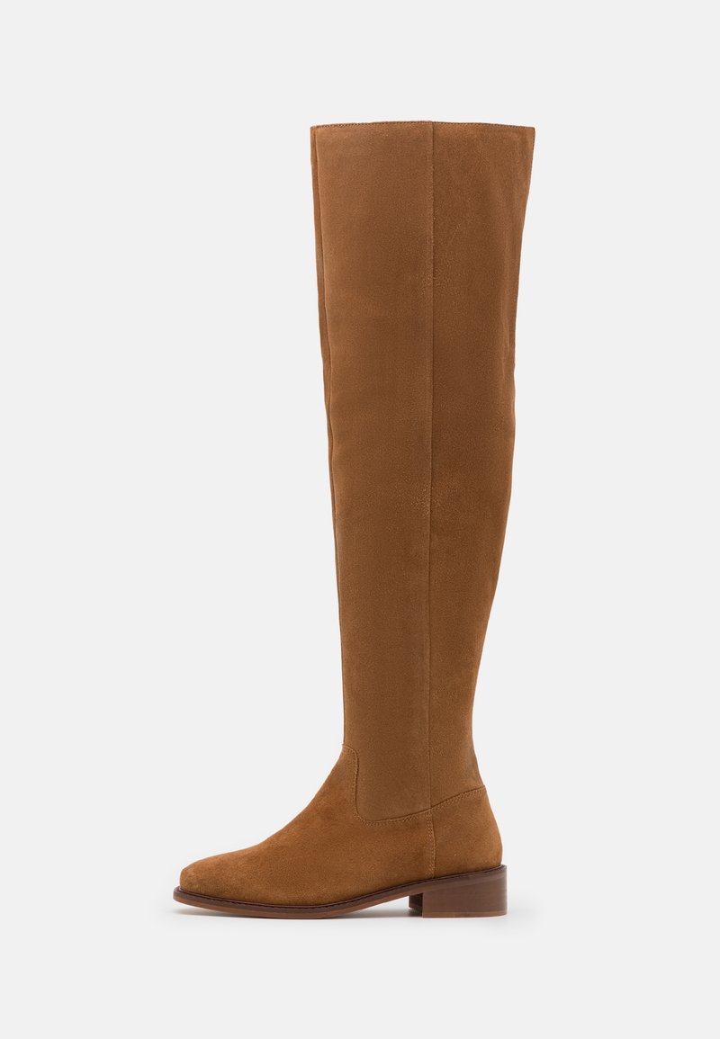 Botte haute en daim marron jusqu'au genou avec un petit talon bloc et un bout arrondi, vue de côté sur fond blanc.