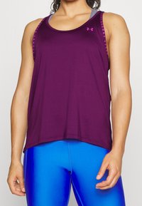 Fioletowy sportowy top na ramiączkach z zaokrąglonym dekoltem i cienkimi paskami, z subtelnym logo oraz luźnym, przewiewnym krojem.