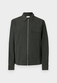 Ciemnozielona kurtka z białymi pionowymi paskami, z zamkiem błyskawicznym, kołnierzem i kieszenią na piersi. Ma długie rękawy z mankietami na guziki.