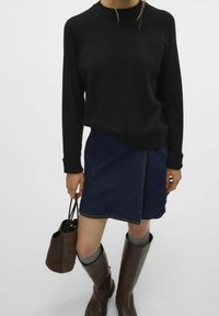 Czarny sweter z długim rękawem z prążkowanymi akcentami, zestawiony z ciemnoniebieską spódnicą dżinsową z bocznym rozcięciem. Szare skarpetki do kolan i brązowe skórzane botki.