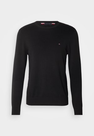 Zwarte gebreide trui met een ronde hals, lange mouwen en een klein logoaccent in rood, wit en blauw op de borst. Zachte textuur.