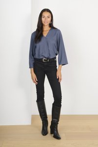 Blusa blu con pois testurizzati, scollatura a V e maniche larghe. Abbinata a jeans skinny neri e stivali neri di pelle fino al ginocchio.