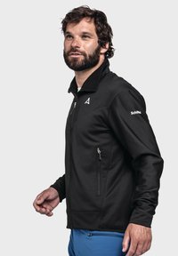 Schwarze Fleecejacke mit Reißverschluss vorne, hohem Kragen und Seitentaschen. Mit einem Logo auf der Brust und einem strukturierten Stoff.