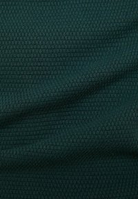 Tissu tricoté vert foncé avec un motif côtelé texturé et de légers plis créant des ombres douces.