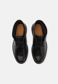 Black leather dress shoes with a smooth finish, rounded toe, and minimal lacing. Interior features a light brown padded insole.