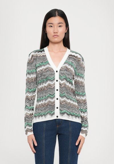 Cardigan im Zickzackmuster, in den Farben Grün, Schwarz und Weiß, mit V-Ausschnitt, langen Ärmeln und schwarzen Knöpfen vorne.