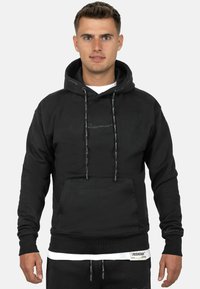 Felpa nera con cappuccio, tasca frontale, cappuccio con lacci e dettagli del logo grigi sul petto e sul polsino. Tessuto morbido, polsini e fondo a costine.