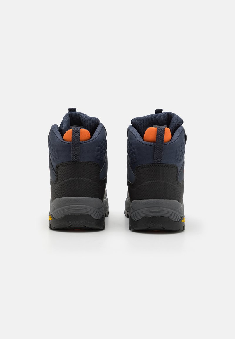 Scarpe da trekking mid-top con superiore in tessuto nero e blu navy, dettagli arancioni, tallone testurizzato e suola in gomma grigia robusta. Inclusi i lacci posteriori per il tiro.