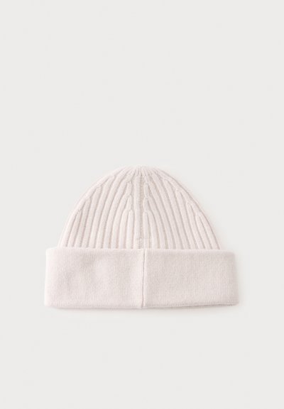 Bonnet blanc tricoté avec revers plié et motif torsadé vertical sur fond clair.