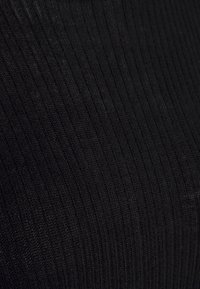 Tecido ribbed preto, de peso médio, com uma textura suave. O padrão apresenta linhas verticais criadas por pontos de malha alternados.