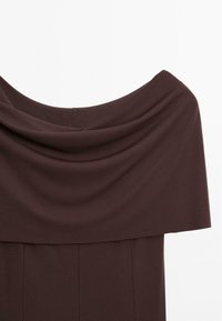 Robe décolletée en tissu marron foncé, avec un col drapé, un corsage structuré et une transition fluide vers une jupe droite.