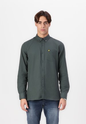 Dark green button-up shirt with a chest pocket and a small yellow logo. Made from a smooth fabric, featuring long sleeves and a classic collar.