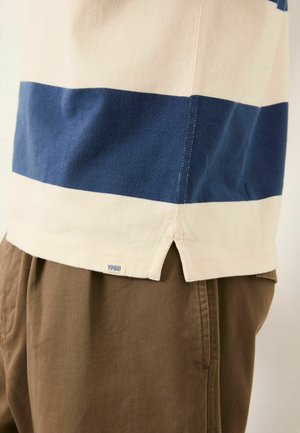 Striped cotton t-shirt featuring navy and cream horizontal stripes, side slits at the hem, and a label with "1988" on the back bottom.