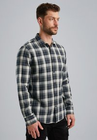 Gekoekte blouse met lange mouwen in zwart, grijs en crèmekleurige stof; knoopsluiting aan de voorkant; geborduurd logo op de linkerkant van de borst; klassieke kraag.