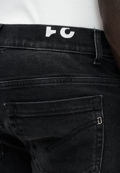 Μαύρο τζιν από τζιν ύφασμα με λευκό λογότυπο στη μέση της μέσης, με πίσω τσέπες και μικρό μεταλλικό λογότυπο στην δεξιά τσέπη.
