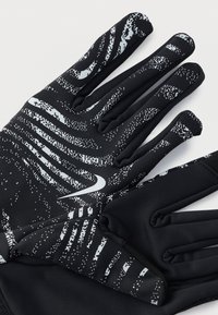 Μαύρα γάντια με υφή προτύπου από λευκές κουκίδες και γραμμές. Κατασκευασμένα από ευέλικτο υλικό, με ανάγλυφο λογότυπο στην παλάμη.