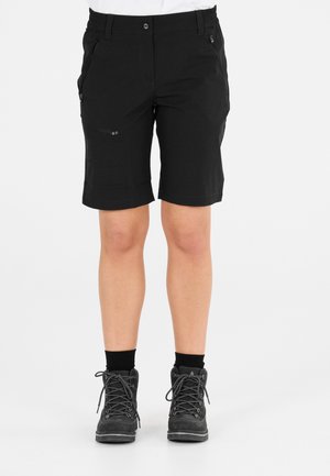Sorte cargo knælange shorts med lynlåslommer, der bæres med sorte sokker og vandrestøvler mod en ensfarvet baggrund.