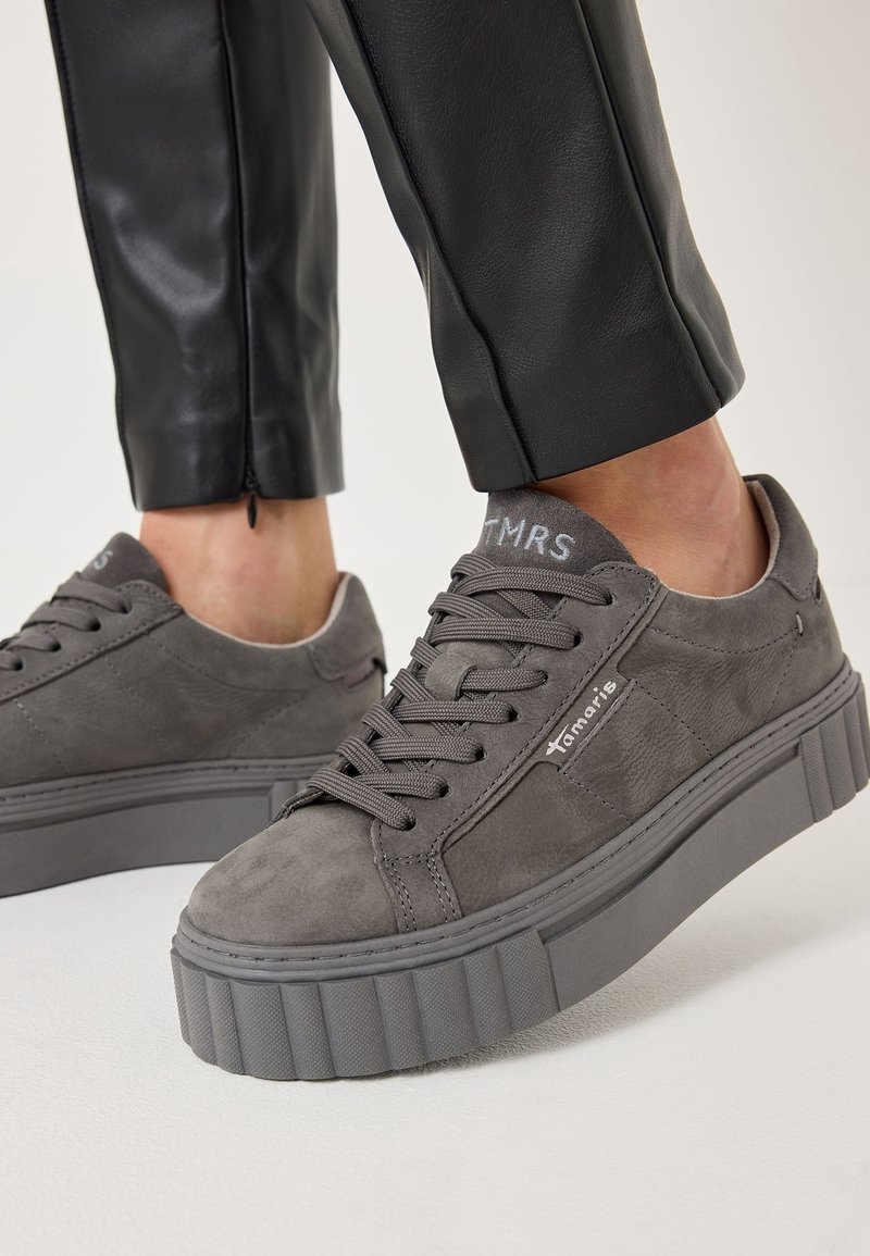 Baskets compensées en daim gris avec lacets ronds, logo sur le côté et semelle texturée. Accentuées par une semelle intermédiaire en caoutchouc texturé et des détails de couture.