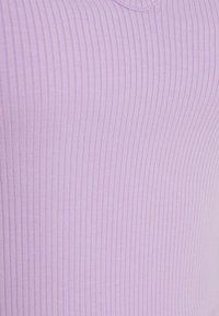 Gros plan sur un tissu côtelé violet clair avec un motif de tricot vertical et un col arrondi.