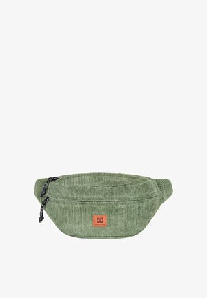 Groene corduroy heupriem met een ronde vorm, voorzien van een leren logo patch en zwarte ritsaccenten. Textuur oppervlak en verstelbare schouderband.