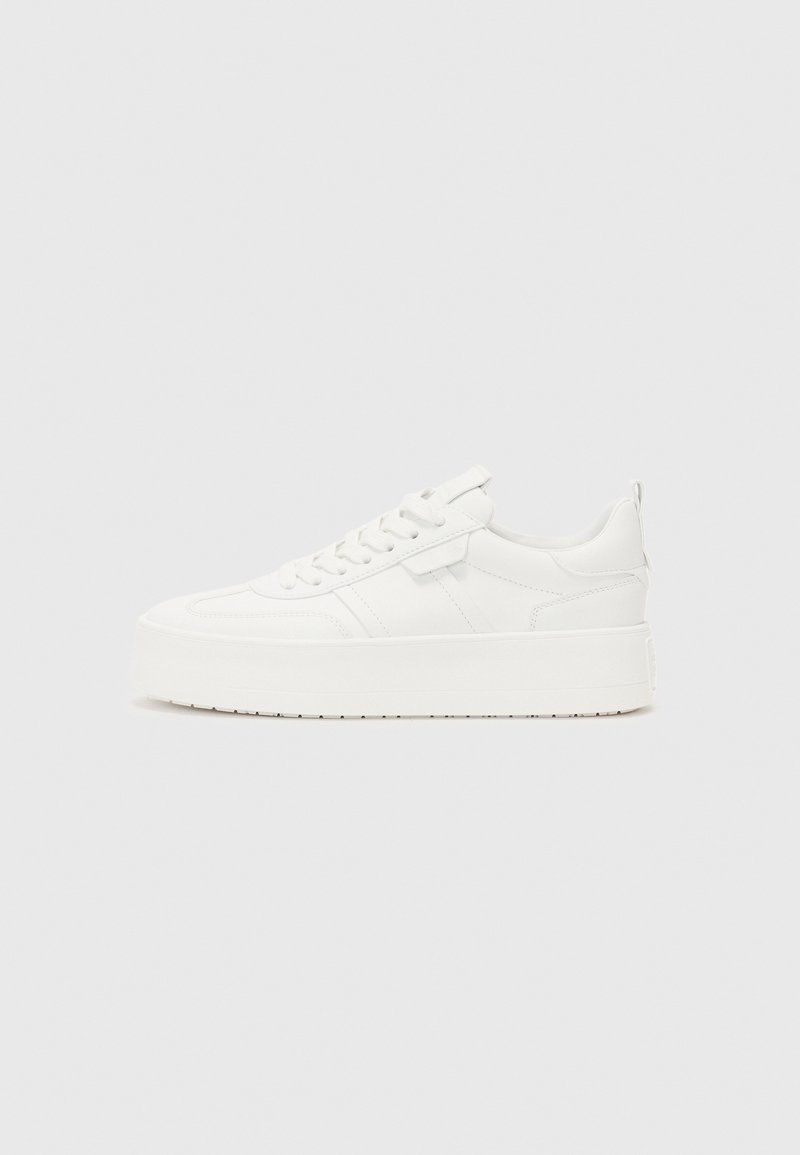 Baskets blanches à plateforme avec lacets à l'avant et col rembourré, vues de profil sur un fond clair uni.