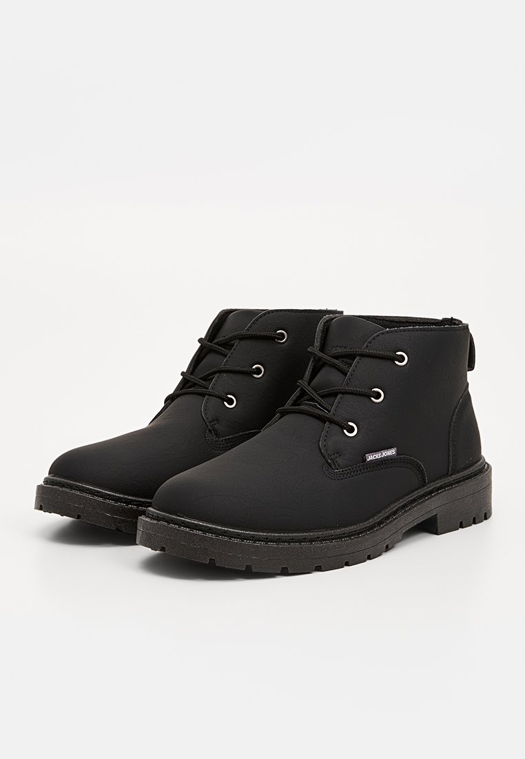 Bottes noires à la cheville avec un dessus en synthétique lisse, à lacets sur le devant et à bout rond. Comprend une semelle en caoutchouc avec un motif texturé et un accent de marque.