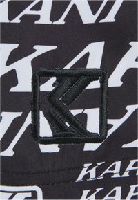 Fekete textil folt, fehér és fekete "KAR" felirattal. Középen elhelyezett logó fekete hímzéssel, négyzet alakban, textúrázott részletezéssel.