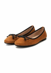Bailarinas de ante color tan con punta redondeada, ribete negro y acento de lazo. La suela es plana y ofrece un diseño simple y limpio.