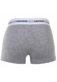 Szare bawełniane bokserki z białą elastyczną gumką z logo "LACOSTE" w kolorze czarnym, gładka tekstura i dopasowany krój.