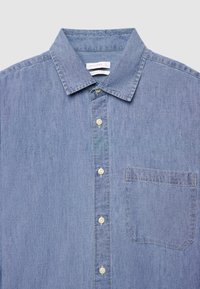 Hellblaues Jeanshemd mit spitzem Kragen, Knopfleiste und einer Brusttasche auf der linken Seite. Weiche Textur mit verwaschenem Finish und klassischem Design.