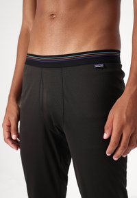Svarta tights för träning med en texturerad yta, som har en flerfärgad elastisk midja och en åtsittande design.