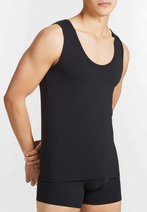 Top in cotone nero senza maniche con scollatura arrotondata e fori per le braccia, caratterizzato da un design aderente e da una texture liscia. Abbinato a pantaloni corti neri coordinati.