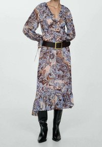 Dlouhé vzorované šaty s volánky na výstřihu a spodním lemu. Obsahují kombinaci modrých, hnědých a růžových paisley vzorů, doplněné černým páskem.
