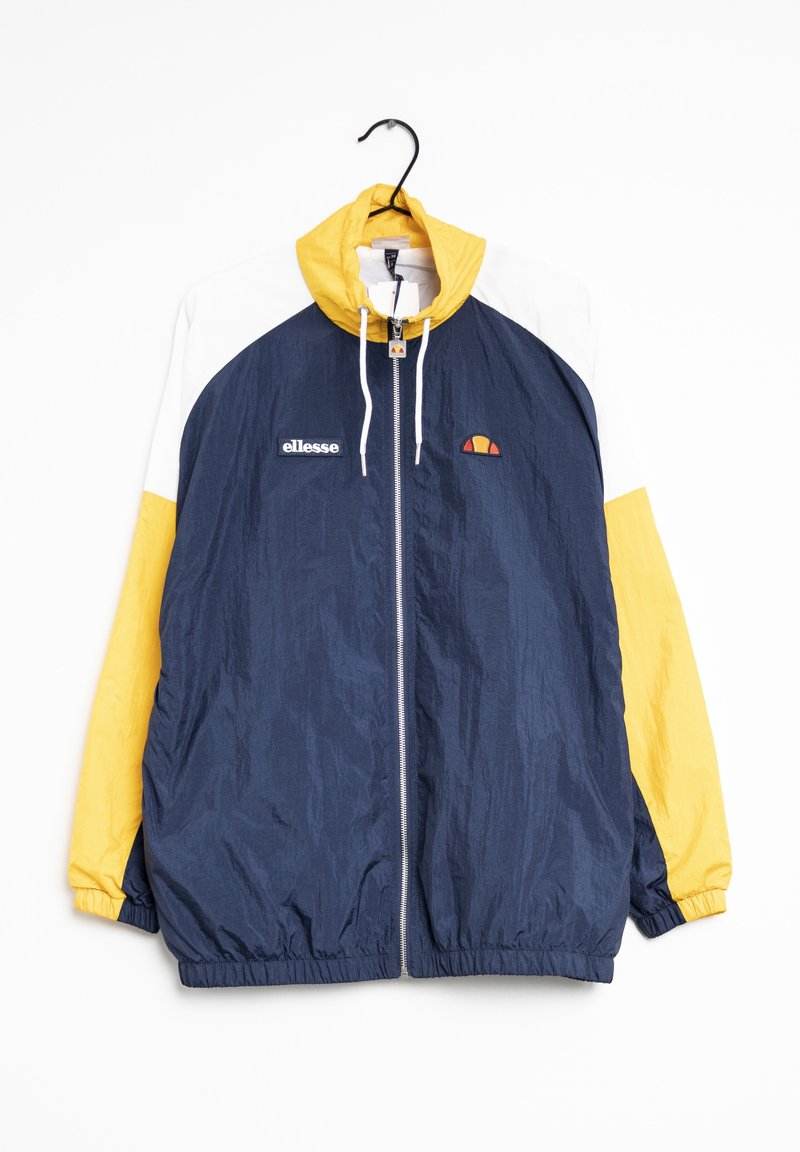 Coupe-vent colorblock avec corps bleu marine, manches et capuche jaunes, épaules blanches, fermeture éclair devant et logo ellesse sur la poitrine, suspendu sur un cintre.