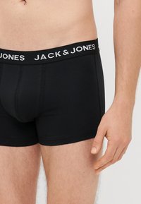 Črne bombažne bokserice s elastičnim pasom blagovne znamke, ki vsebuje belo napis "JACK & JONES", zasnovane za prileganje.