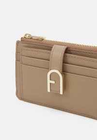 Brown leather wallet featuring a gold zipper, an embossed logo, multiple card slots, and sleek stitching details.