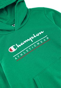 Felpa verde in cotone, con tasca frontale, cappuccio regolabile e logo stampato "Champion" con la scritta "ATHLETICWEAR" in bianco e rosso.