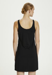 Schwarzes ärmelloses Kleid mit Rundrücken, aus weichem Stoff, mit tailliertem Oberteil und einer Raffung im unteren Rückenbereich.