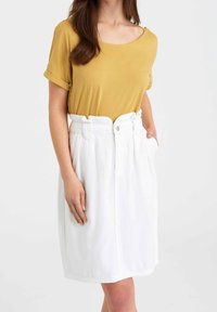 Mustard yellow short-sleeve top paired with a high-waisted white skirt featuring pockets and button closure. Smooth fabric, relaxed fit.