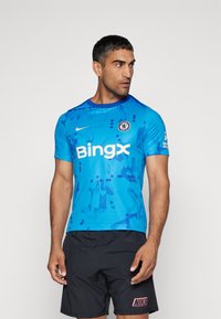 Camisa atlética azul con un patrón abstracto, logo de Nike y la marca "Bingx" en el frente, con un cuello redondo y mangas cortas.
