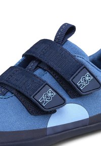 Sneaker in tessuto blu con una superficie strutturata, dotate di due cinturini in Velcro neri. Le rifiniture includono dettagli a forma di orso e un design della punta arrotondata.