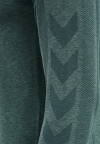 Vihreät urheiluhousut, joissa on tekstuuri, viisto kuvio sivuilla, ja sileä pinta lisämukavuutta ja joustavuutta varten.