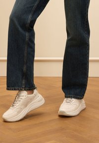 Witte sneaker met een gestructureerde bovenkant, vetersluiting en gevoerde tong. Draagt samen met donkere spijkerbroeken, met een rechte snit en subtiele stiksels.