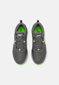 Gray athletic shoes with mesh upper, green accents, and textured rubber sole. Features standard laces and small pull tabs at the heel.