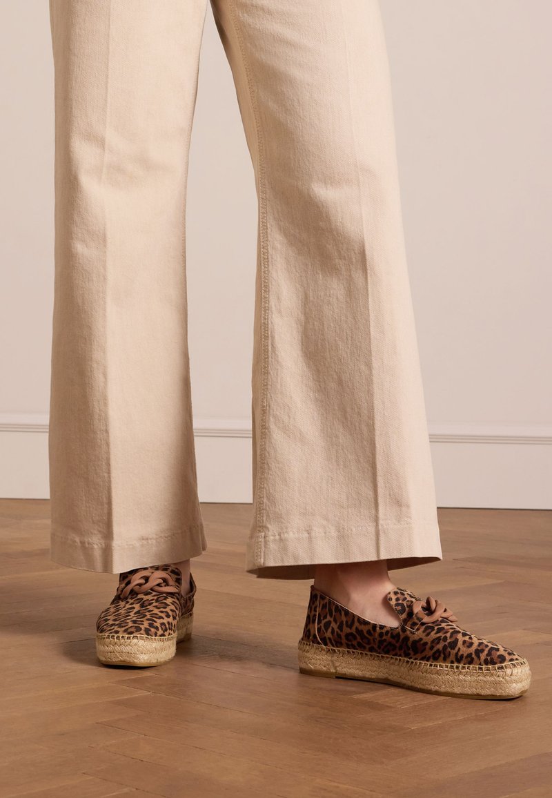 Leopardprint espadrilles met een jute zool, voorzien van bruine veters en een rondneus ontwerp, gecombineerd met beige wijde broek.
