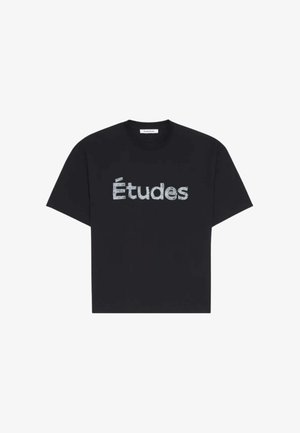 T-shirt noir à manches courtes avec "Études" imprimé en lettres texturées bleu clair sur la poitrine, col rond.