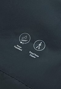Waterafstotende en EasyClose-ritssluitingspictogrammen gedrukt op donkere stof, die de kenmerken van het kledingstuk benadrukken.