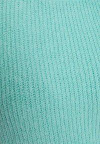 Tessuto lavorato a maglia azzurro chiaro con texture a coste verticali, che mostra fibre morbide e pelose e un pattern coerente su tutta la superficie.