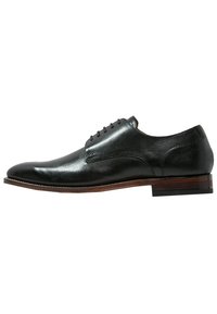 Chaussure de ville en cuir noir avec une finition brillante, bout arrondi, cinq œillets et un talon en bois empilé. Design élégant avec un minimum de coutures.